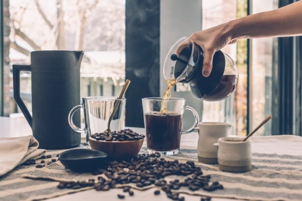 A woman pours freshly brewed coffee into a cup