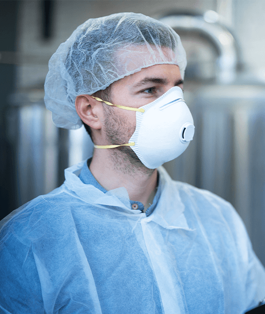 Man wearing hair net, mask, and apron