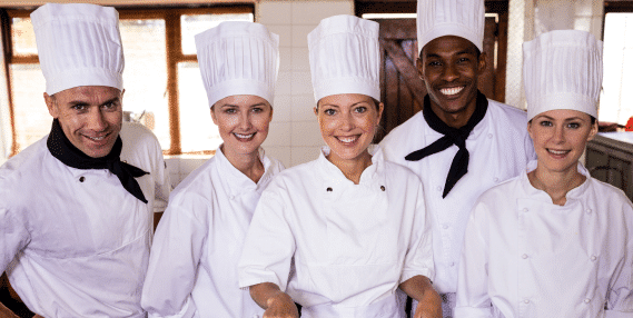 Five kitchen staff members who have food safety certification wearing chef uniforms.