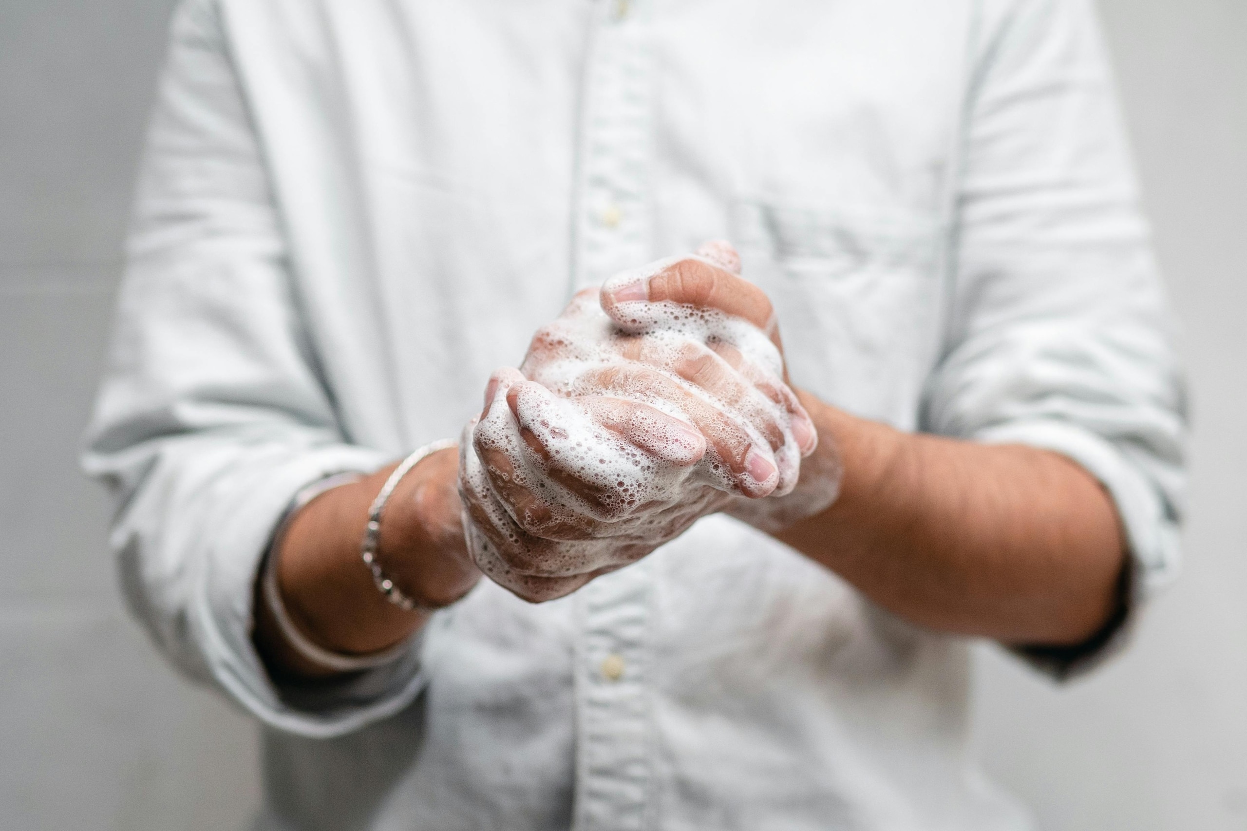 Close-up of a person washing their hands with soap, creating a lather of bubbles. The focus is on the hands and the importance of proper hand hygiene, emphasizing cleanliness and safety.